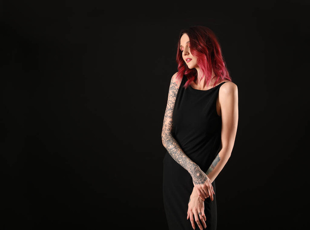 Beautiful woman with tattoos on arms against black background. Space for text - Zdjęcie, obraz