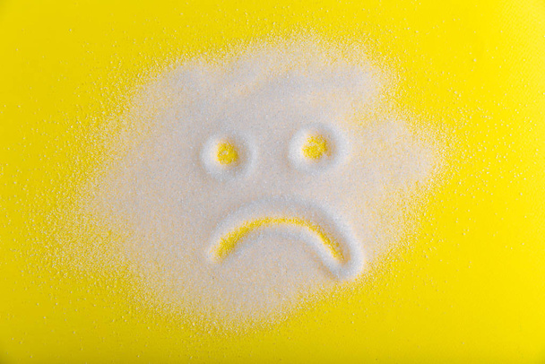 Сахар это плохо. Грустное сахарное лицо на желтом фоне
. - Фото, изображение