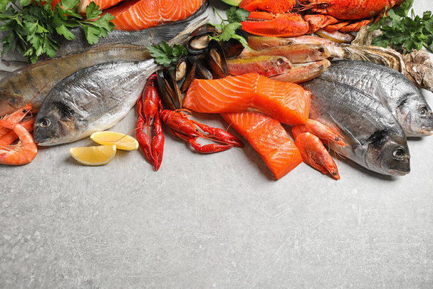 Fresh raw fish and different seafood on light grey table. Space for text - Photo, Image