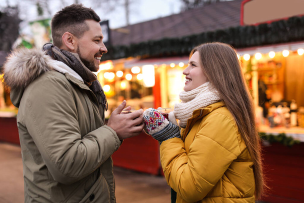 Happy couple with mulled wine at winter fair - 写真・画像