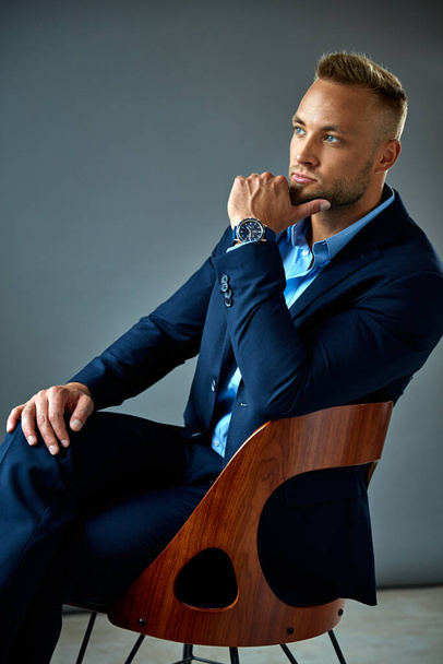 Young elegant man in blue suit touching chin and thinking  - Foto, afbeelding