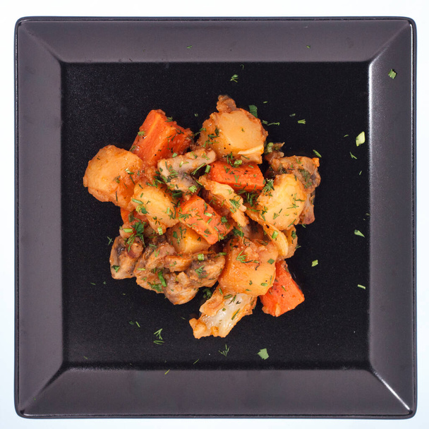Stew potatoes on a black plate. White background - Photo, Image