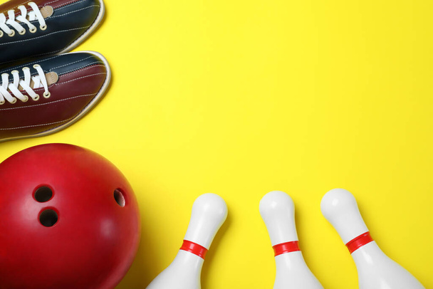 Bowling ball, shoes and pins on yellow background, flat lay. Spa - Foto, immagini