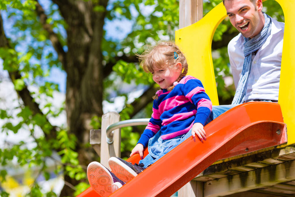 father and daughter on slide at playground - Photo, image