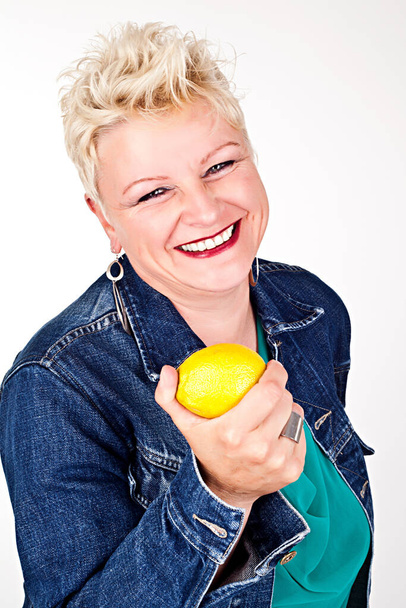 portrait of middelaged beautiful woman eating fresh lemon - Foto, immagini