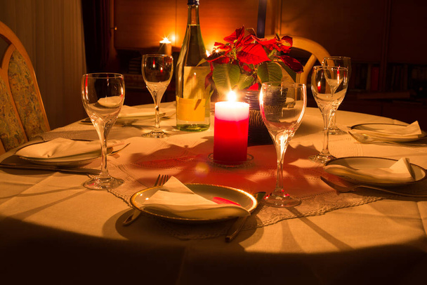 Dinnertable at candlelight with flowers, glasses and plates - Photo, image