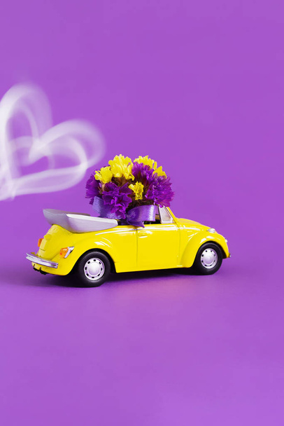 Вид на желтый кабриолет с букетом цветов на фиолетовом фоне, за которым развивается поезд белого сердца. Праздник, доставка, искусство, фон, транспорт
 - Фото, изображение