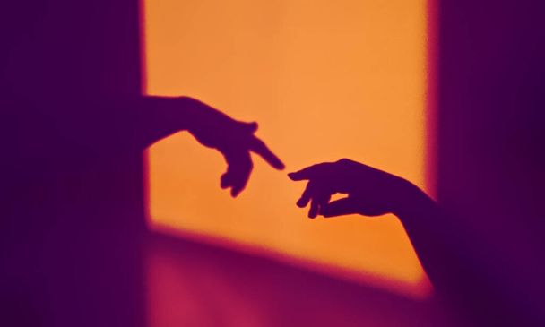 Abstract schaduw silhouet van gebaar aanraking door mensen palmen in contrasterende kleuren - Foto, afbeelding