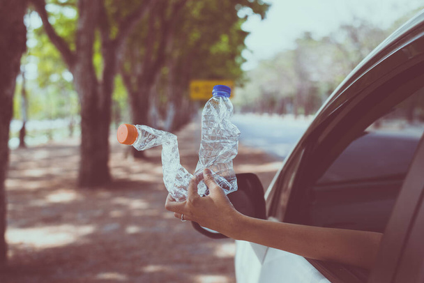 Woman hand holding plastic bottle on the road,Global warming environmental protection concept - Foto, immagini