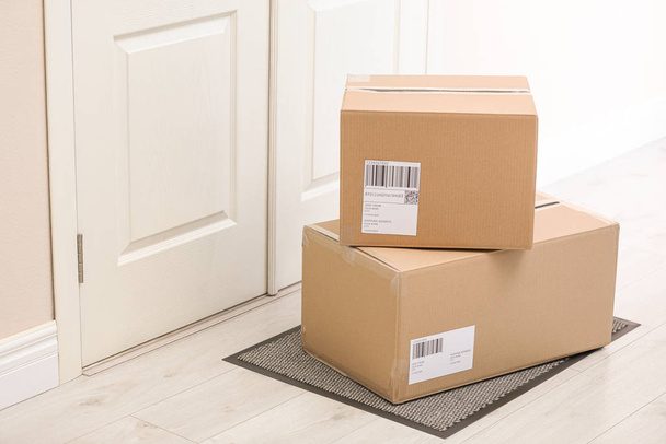 Parcels on rug near door. Delivery service - Photo, image