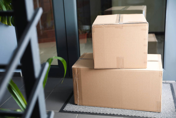 Cardboard boxes on rug near door. Parcel delivery service - Фото, изображение