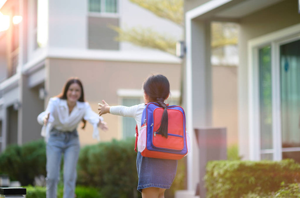 menina filha correndo emocionante para a mãe bem-vindo em casa depois do estudo da escola
 - Foto, Imagem