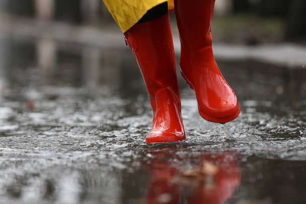 Woman in rubber boots walking outdoors on rainy day, closeup. Sp - Фото, изображение