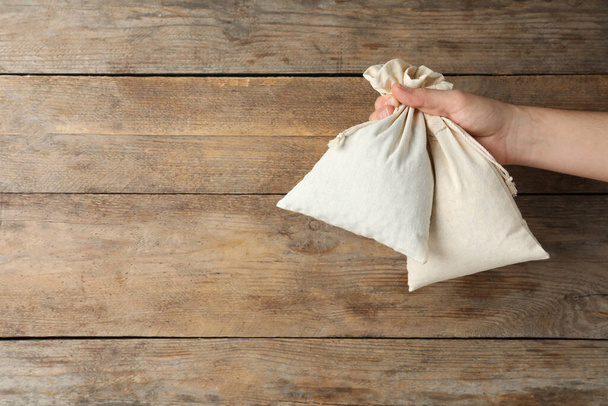Woman holding full cotton eco bags on wooden background, closeup. Space for text - Φωτογραφία, εικόνα