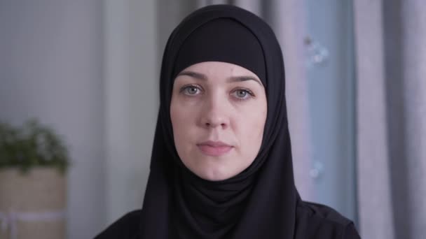 Close-up portrait of young beautiful Muslim woman in traditional black hijab. Charming lady looking at camera. Beauty, style, culture, lifestyle. - Filmagem, Vídeo