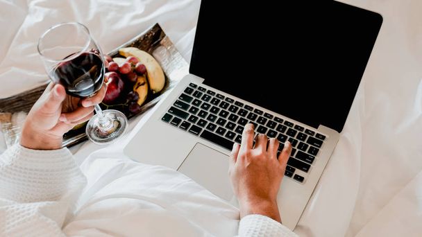 Imagem de turistas usado laptop e comer frutas na cama, conceito de comida saudável
 - Foto, Imagem