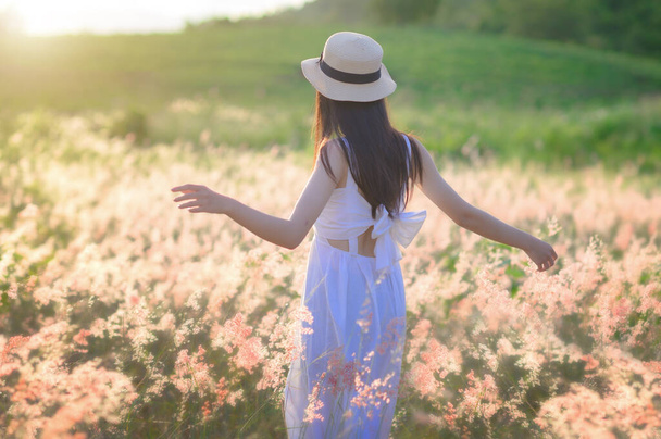 young woman walks feel freedom in the light of warm sun, bloom of wild flowers in meadow, enjoyment and peaceful in the field of meadow - Photo, Image