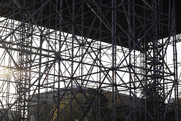 Yapı, hafif metal inşaat borularının birleşmesiyle oluşmuş. Gün batımında güneş ışığı. - Fotoğraf, Görsel