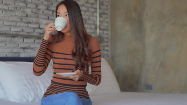 footage of beautiful asian woman drinking coffee at home - Кадри, відео