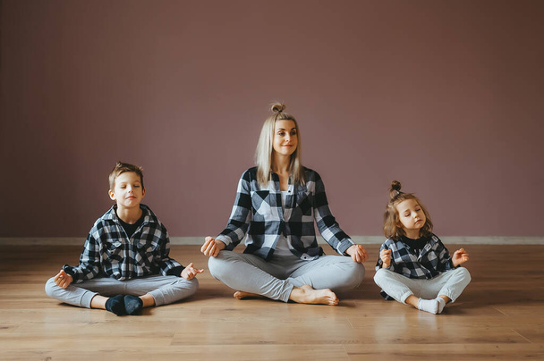 Familia joven de madre e hijos hijo e hija se dedican al yoga, ejercicio en el gimnasio
. - Foto, imagen