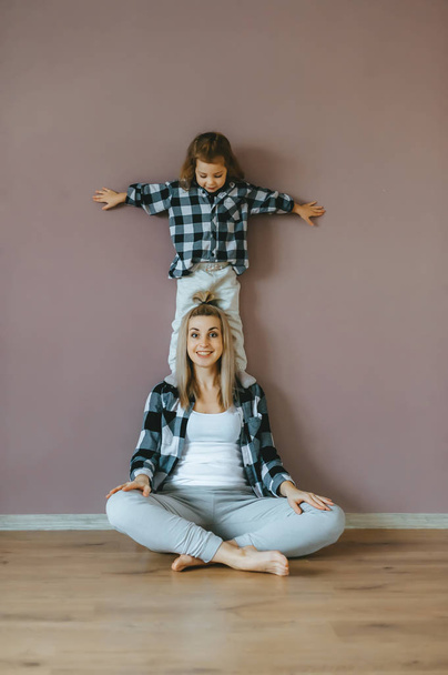 Mutter mit Kind praktiziert Yoga in Lotus-Pose. - Foto, Bild