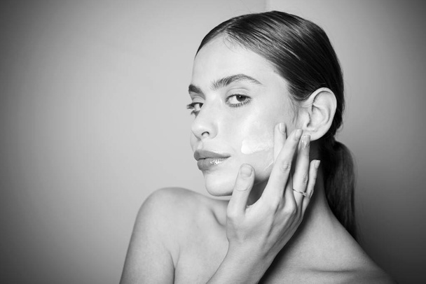 Sexy healthy woman applying cream or lotion with moisturizer to skin face. Perfect pure skin. Healthy and wellness concept. Natural beauty and no make up concept. - 写真・画像