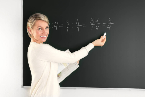 teacher standing at blackboard and writes - Valokuva, kuva