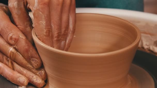 Mans hands sculpting a pot out from the clay on a potter wheel - Footage, Video