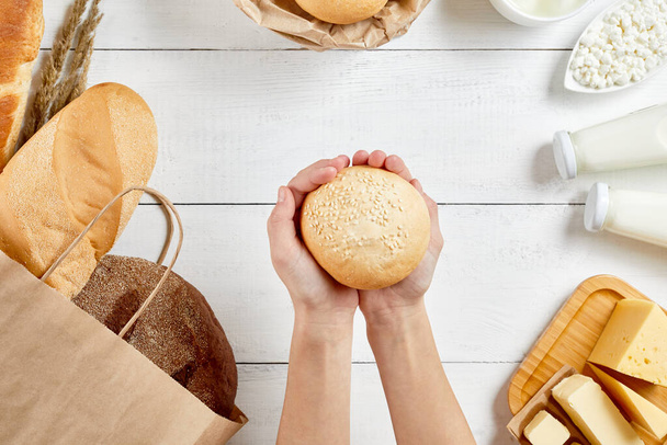 Bread in ecology paper bag. Natural organic food: milk, cheese and bakery. Zero waste recycling. Female hands gives bun - Photo, image