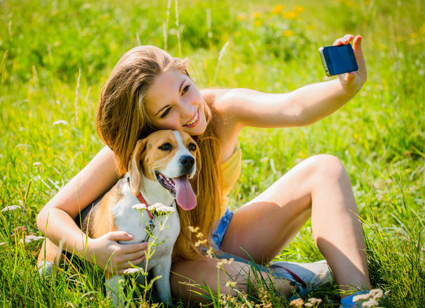 Teen girl taking photo of herself and her dog with mobile phone camera - Foto, Imagem