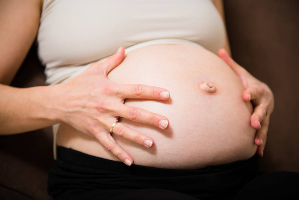 Detail of hands holding pregnant belly - indoors - Foto, imagen
