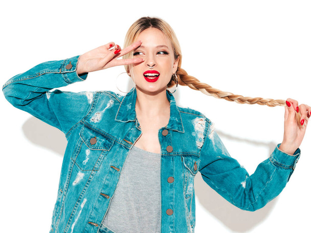 Portrait of young beautiful hipster bad girl in trendy jeans summer clothes and earring in her nose.Sexy carefree smiling blond woman posing in studio.Positive model having fun.Shows peace sign - Φωτογραφία, εικόνα