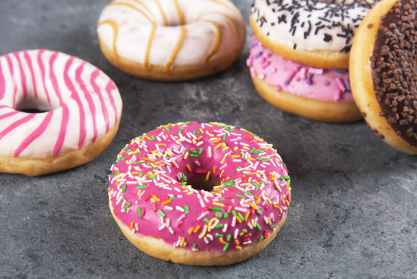 Bakken zoete heerlijke donuts met gebak kruimel op grijze betonnen achtergrond. Voedseltextuur - Foto, afbeelding