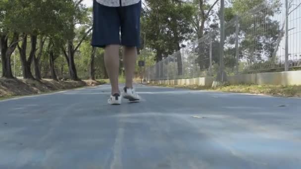 Nízký úhel pohledu zezadu ženy nohy chůze na silnici ve veřejném parku během léta. - Záběry, video