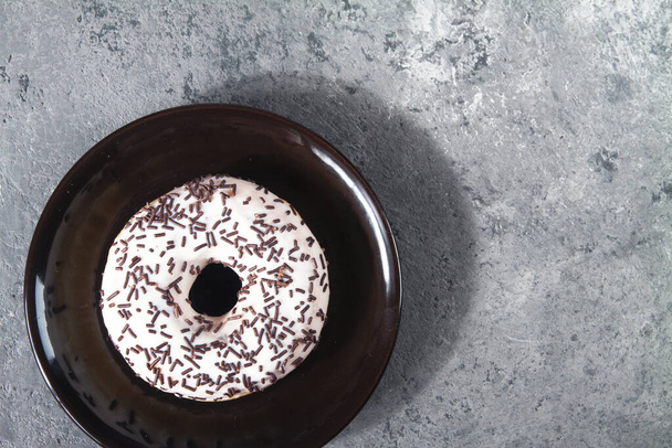 Pečené sladké lahodné koblihy s drobenkou pečiva na šedém betonovém pozadí. Struktura potravin - Fotografie, Obrázek