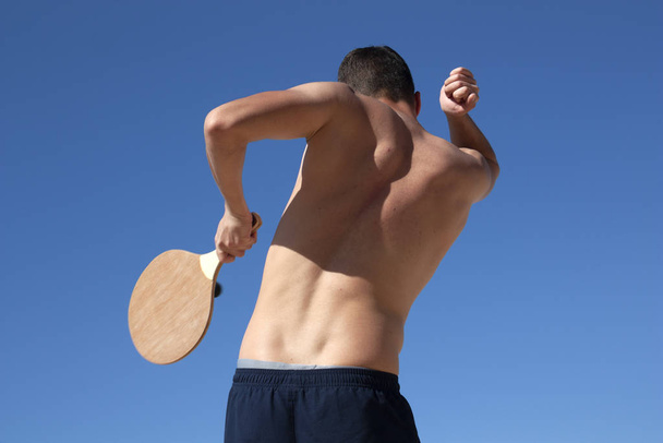 The guy plays matkot on the beach - Фото, изображение