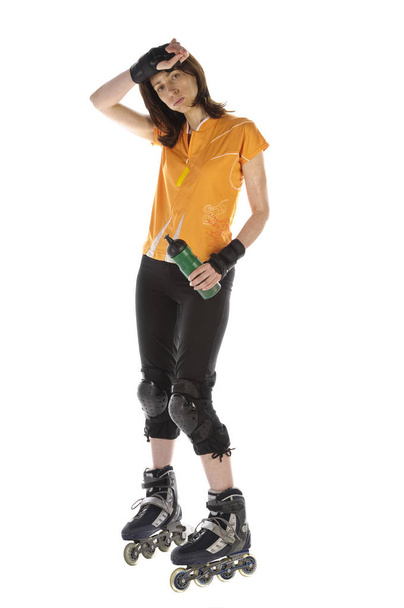 adult woman doing sports on inline skates and drinking from her water bottle against white background - Foto, immagini