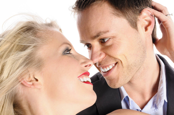 a young man in a dark suit and an attractive blond woman stand isolated against white background,hugging and kissing each other. - Photo, Image