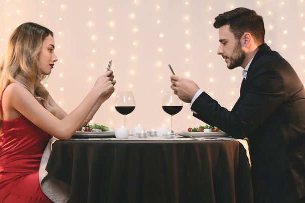 Restoranda randevularında birbirini görmezden gelen, telefonlara takılan çift. - Fotoğraf, Görsel
