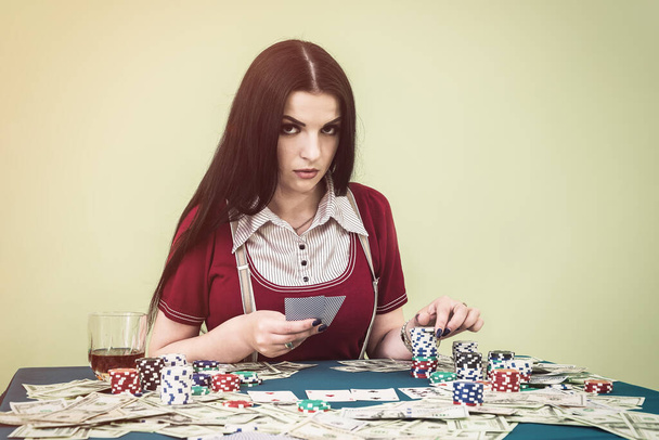 Attractive brunette woman with playing cards and poker table - 写真・画像