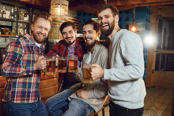 A group of friends is sitting in a bar with glasses of beer. - Foto, imagen