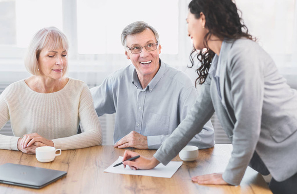 Happy mature couple talking to financial advisor at office - Photo, Image
