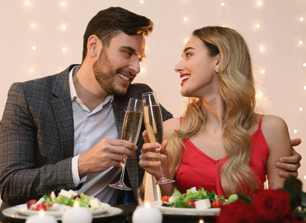 Jeune couple ayant soirée romantique au restaurant, lunettes clinking avec champagne
 - Photo, image