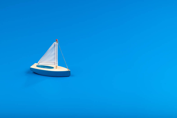 Little blue toy boat exploring the blue ocean. - Zdjęcie, obraz