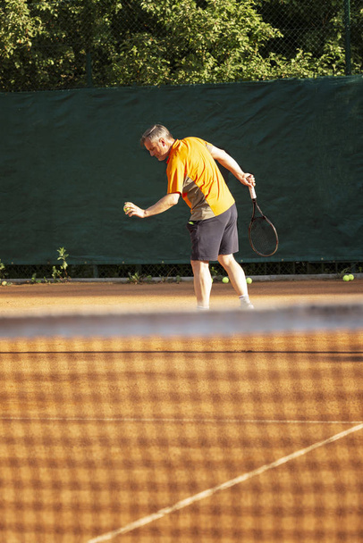 A man plays tennis on the court on a sunny day. Health and activity. - Foto, imagen