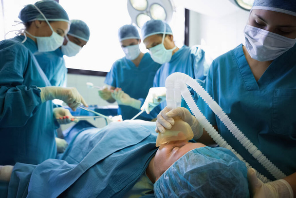 Unconscious patient being operated by surgeons in an operating theater - Foto, Imagen