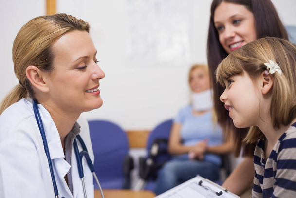 General practitioner talking to a girl in a waiting room in a hospital - Photo, image