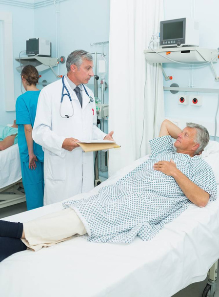 Doctor talking with a patient in a bed ward in a hospital - Photo, image