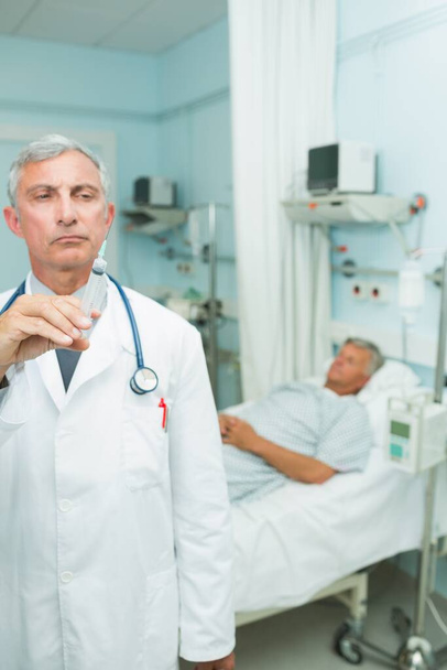 Medico serio con una siringa in mano in una stanza d'ospedale - Foto, immagini