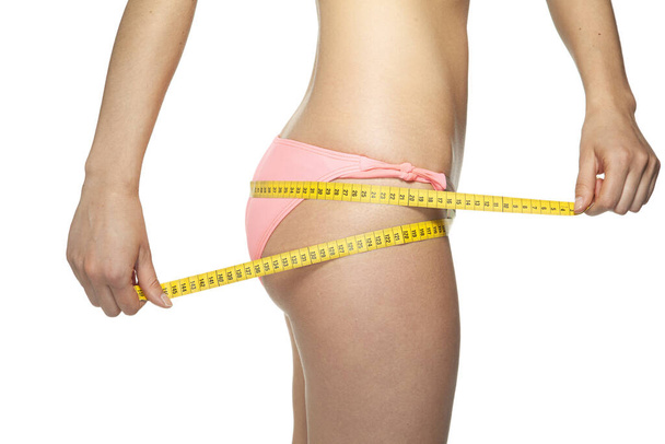 a woman with a perfect figure uses a measuring tape to measure h - Photo, Image